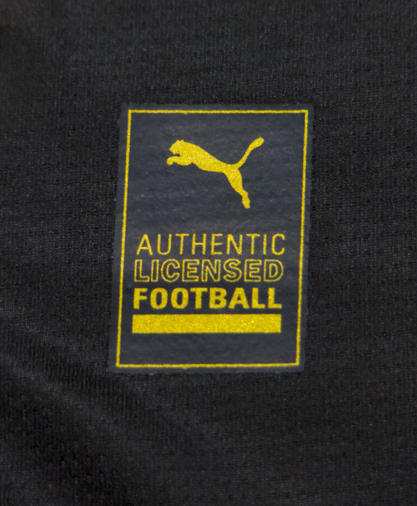 Imagen de un zoom del detalle de la etiqueta de PUMA, de la camiseta local del Borussia Dortmund para la temporada 2023-2024.