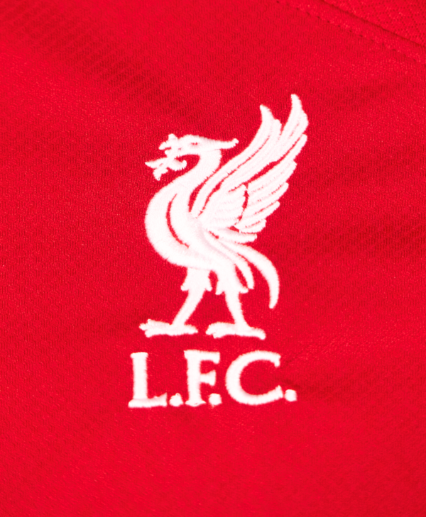 Imagen de un zoom en el detalle del escudo del equipo en la camiseta local del Liverpool para la temporada 2023-2024.