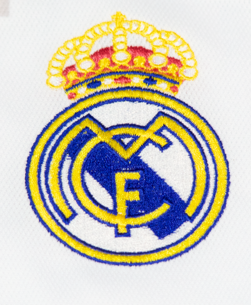 Imagen de un zoom en el escudo de la camiseta local del Real Madrid para la temporada 2023-2024.