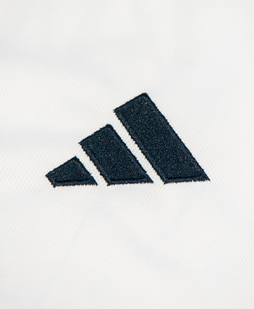 Imagen de un zoom en el icono de Adidas en la camiseta local del Real Madrid para la temporada 2023-2024.