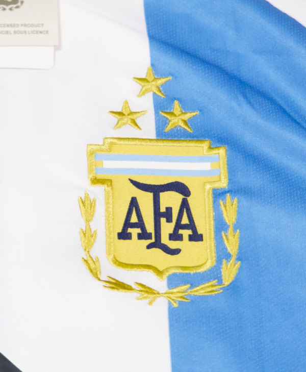 Imagen de un zoom en el escudo de Argentina en la camiseta local de la selección argentina para la temporada 2023-2024, con las 3 estrellas.