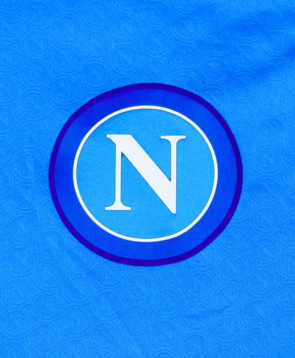 Imagen de un zoom al detalle del escudo del Napoli en la camiseta local para la temporada 2023-2024.